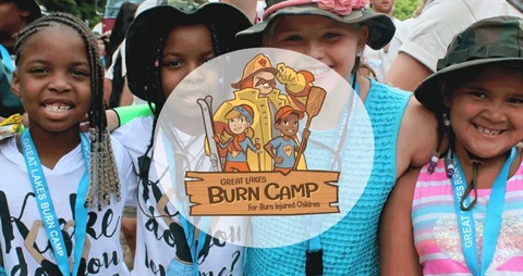 Photo of kids posed behind the logo for Great Lakes Burn Camp